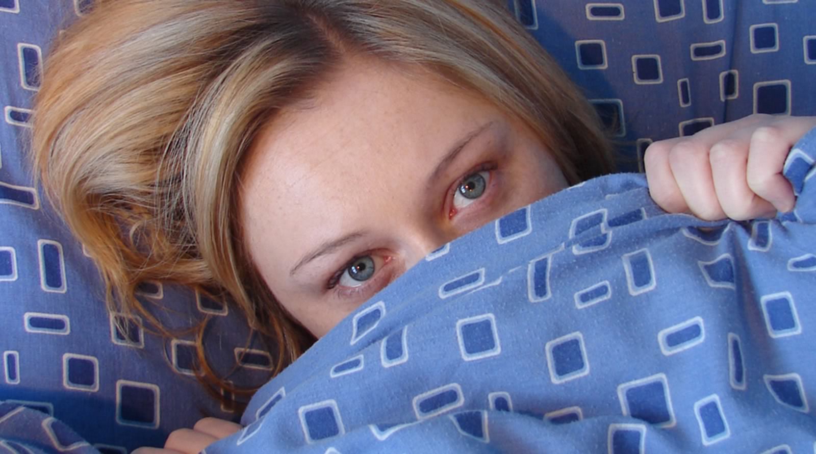 vrouw met gezicht onder dekbed