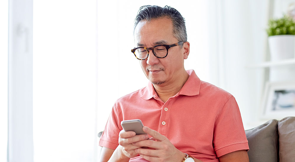 Man zit op de bank en kijk naar zijn mobiele telefoon
