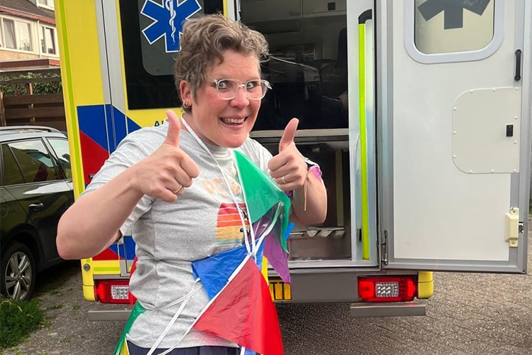Sonja in vlaggetjes gehuld voor een ambulance