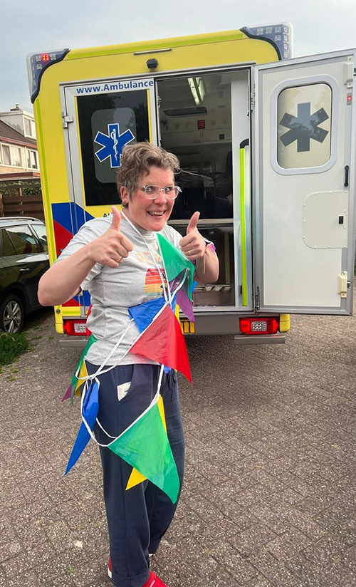 Sonja in vlaggetjes gehuld voor een ambulance